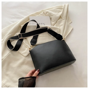 Detail of black faux leather shoulder bag with contrast wide strap and gold hardware