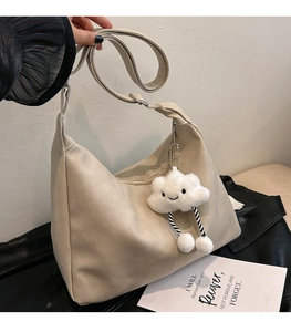 Detail of cream large hobo bag with cloud plush charm and smooth PU leather texture
