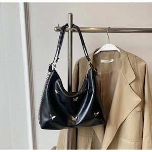 Close-up of black leather hobo bag with silver butterfly patches and metallic chain