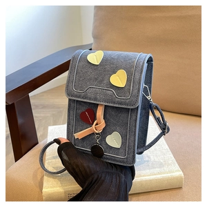 Detail of blue denim cell phone bag with colorful heart patches and knot charm decoration