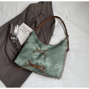 Dettaglio della borsa hobo in camoscio verde con fiocco in pelle e catena argento