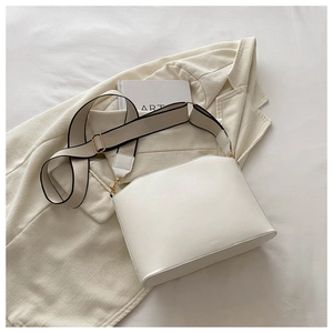 Detail of cream shoulder bag with wide textile strap and gold metal hardware