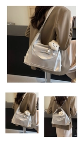 Detail of silver metallic PU tote bag featuring a bow decoration and white cloud plush charm