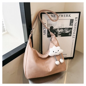 Detail of matte leather tote bag in dusty rose featuring a cute plush cloud charm