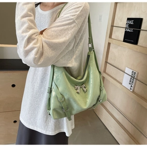 Dettaglio della borsa tote in pelle verniciata verde chiaro con fiocco metallico e fibbie