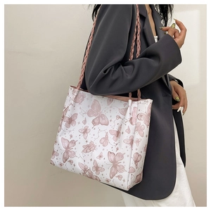 Detailed shot of pink braided handles on a white butterfly print tote bag shown on model