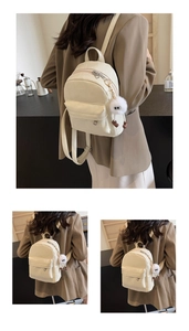 Detail eines cremefarbenen gesteppten Mini-Rucksacks mit Plüschkugel und Reißverschluss