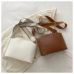 Detail of minimalist cream and tan shoulder bags with wavy edges and wide fabric straps