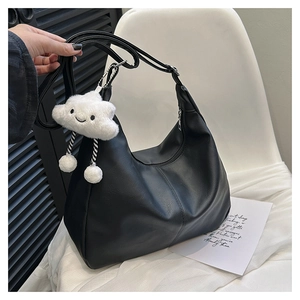Detail of black matte faux leather shoulder bag featuring a white cloud plush charm