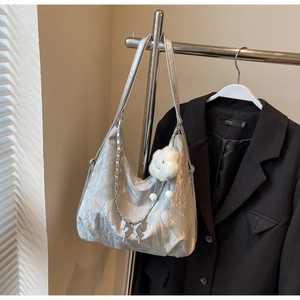Detail view of silver pleated tote bag with butterfly charm and plush cloud accessory