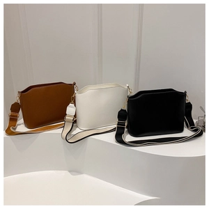 Detailed view of structured leather crossbody bags in brown, white, and black with wide straps