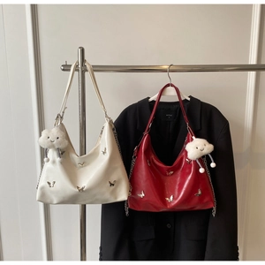 Detail of red and white leather tote bags featuring metal butterfly charms and plush pendants