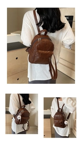 Detail eines braunen PU-Lederrucksacks mit geometrischem Muster und weißem Plüsch-Anhänger
