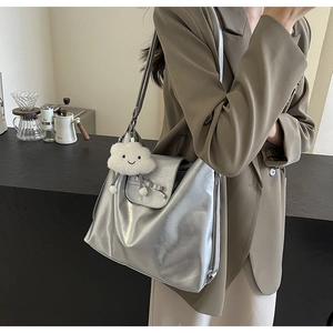 Detalle del bolso tote plateado metalizado con lazo y colgante de peluche de nube blanca