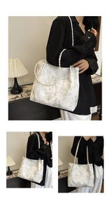 Detail of white tote bag with green butterfly print and woven strap on female model