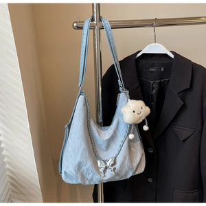 Detail view of light blue tote bag with silver butterfly chain and plush cloud charm