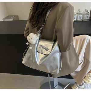 Detalle de un bolso tote plateado metalizado con lazo y un colgante de nube suave
