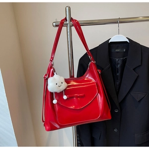 Glossy red large tote bag detail showing exterior bow pocket and cloud charm