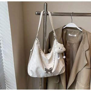 Detail of cream white tote bag with metal butterfly chain and cloud plush pendant