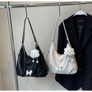 Detail of butterfly pendants and plush cloud charms on pleated tote bags in black and white