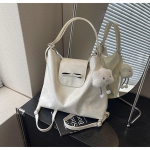 Detalle del bolso tote crema con lazo negro y colgante de nube suave incluido