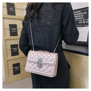 Quilted pink crossbody bag with chain strap shown on a model in a cafe setting