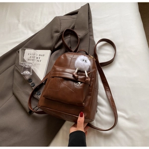 Detail eines dunkelbraunen PU-Lederrucksacks mit geometrischen Nähten und Anhänger