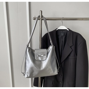 Detalle del bolso tote plateado metalizado con lazo colgado en una percha minimal