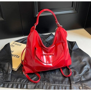 Close-up of red patent leather tote bag with bow detail and adjustable straps on leather