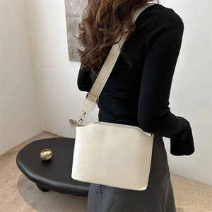 Minimalist cream-colored wide strap shoulder bag in vintage bucket design for women