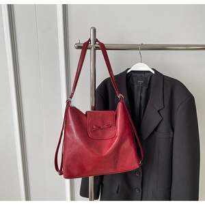 Detalle del bolso tote rojo oscuro con elegante lazo y textura de cuero sintético mate