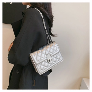 Detail of silver quilted crossbody bag with metal chain strap and turn-lock closure