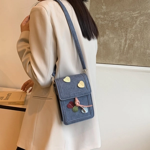 Fashionable denim heart crossbody phone bag worn by a model in a stylish beige blazer