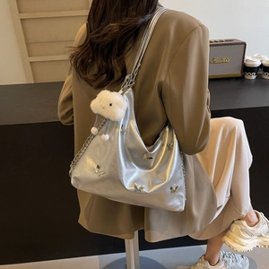 Silver metallic butterfly tote bag with plush charm shown worn over the shoulder