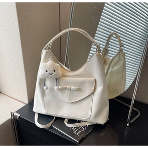 Detail of cream hobo tote bag featuring a bow pocket and cute cloud plush pendant decor