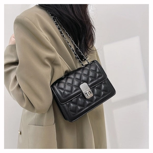 Detail shot of black quilted shoulder bag featuring silver metal twist lock and chain strap