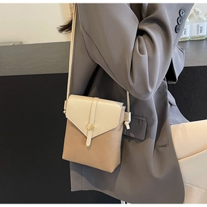 Detail of color-block crossbody bag in lychee pattern leather with metal buckle accent