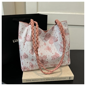 Close-up of butterfly print tote bag with pink woven shoulder straps and artistic patterns