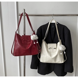Detalle de bolsos tote rojos y crema con lazo y colgante de nube en un soporte de metal
