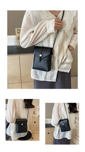 Detail of a black litchi grain leather mobile phone crossbody bag with gold metal buckle