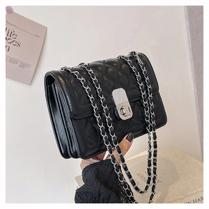 Detail of black quilted leather shoulder bag with silver chain strap and metal clasp