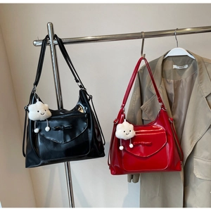 Detail of glossy tote bags with bow flap and plush cloud charms in black and red