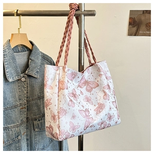Detail of artistic butterfly print and braided shoulder strap on a white tote bag