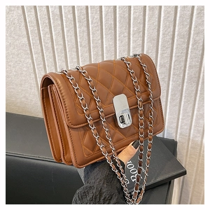 Close-up of brown quilted crossbody bag with silver clasp and chain strap detail
