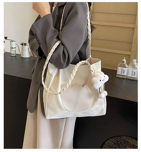 Gros plan d'un sac cabas blanc crème avec bandoulière tissée et pendentif nuage en peluche
