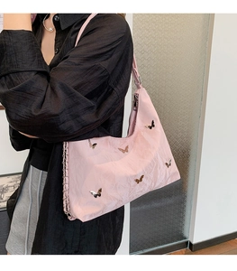 Detailed view of pink nylon shoulder bag with shiny pleated texture and silver butterfly charms