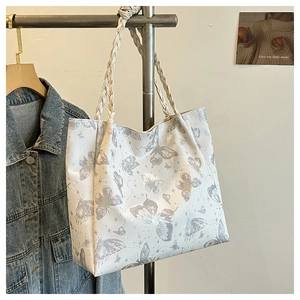 Detail of white butterfly print tote bag with thick beige woven rope handles and leather texture