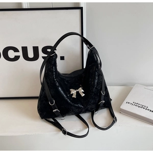 Dettaglio borsa tote in pelle lucida nera con fiocco argentato e fibbie metalliche