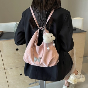 Pink butterfly backpack with silver chain and plush cloud charm worn by a model