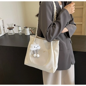 Détail d'un sac cabas en toile crème avec un charm nuage en peluche et des anses tressées